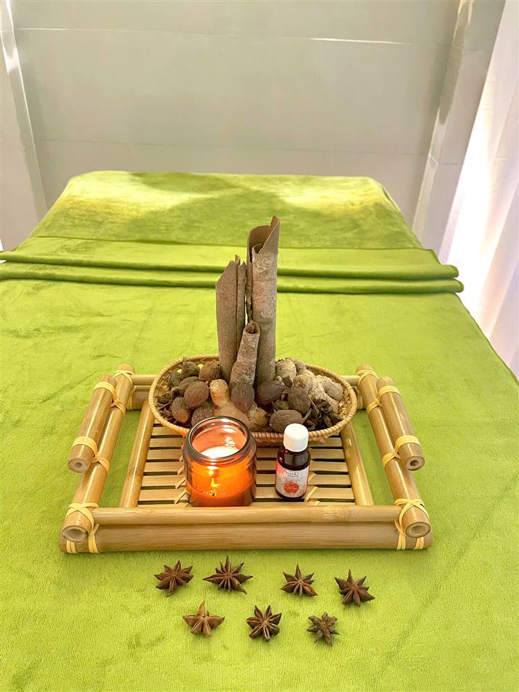 Cinnamon, star anise and a candle on a treatment bed